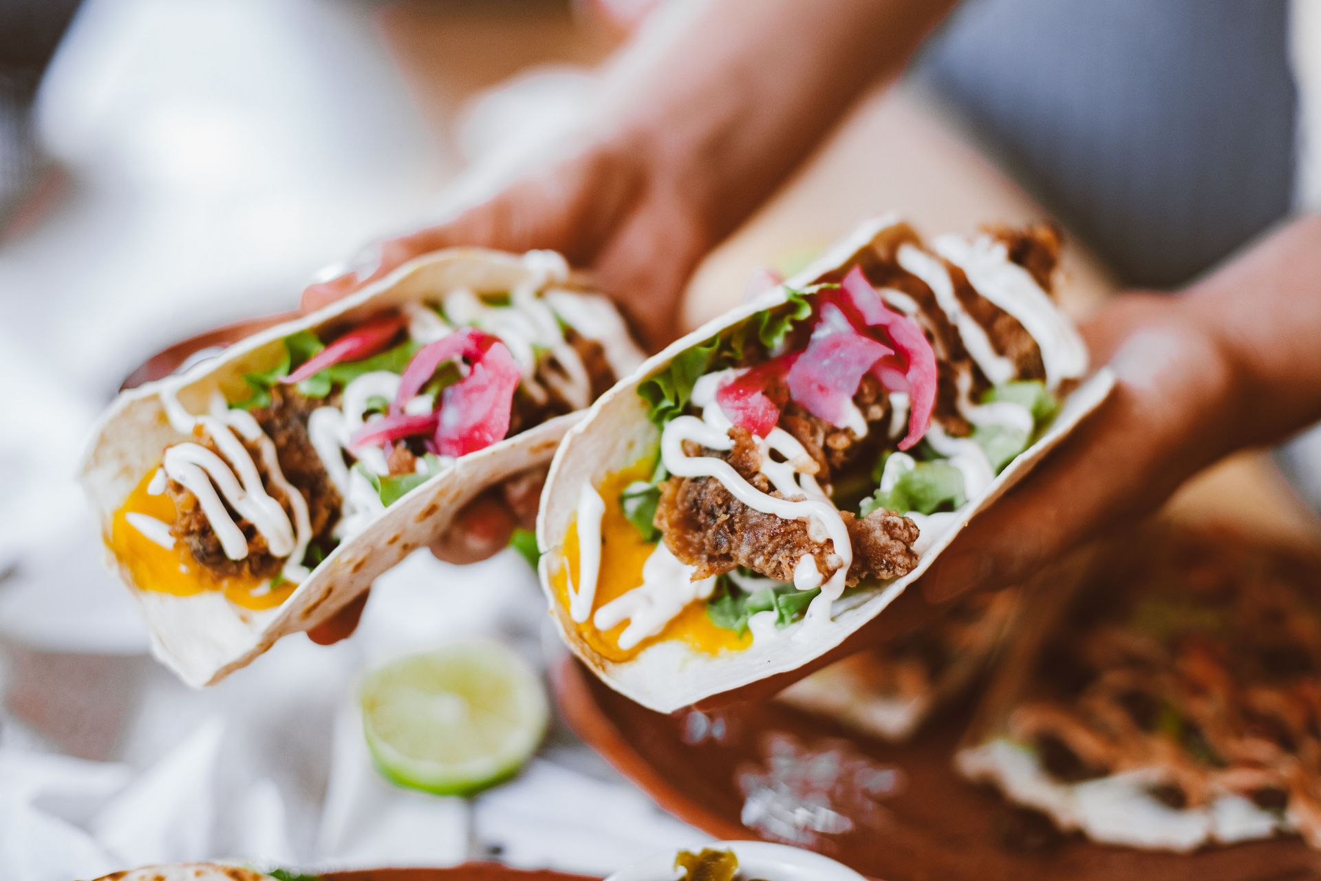 Delicious fresh tacos with fillings including lettuce, cheese, and pickled onions, ready to eat.
